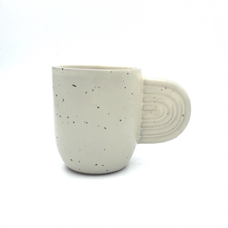Tasse en céramique, de coloris blanc crème moucheté, avec une anse en forme d'oreille